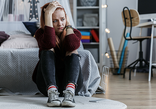 girl holding head in bedroom