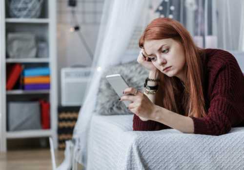 girl checking phone on bed