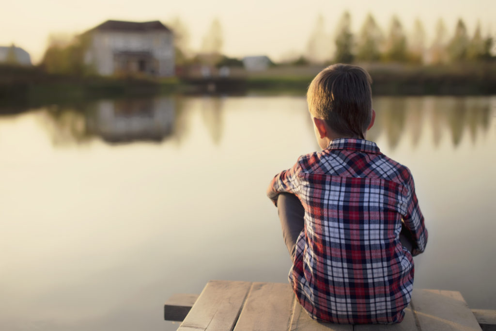 Child with back turned looks out over lake