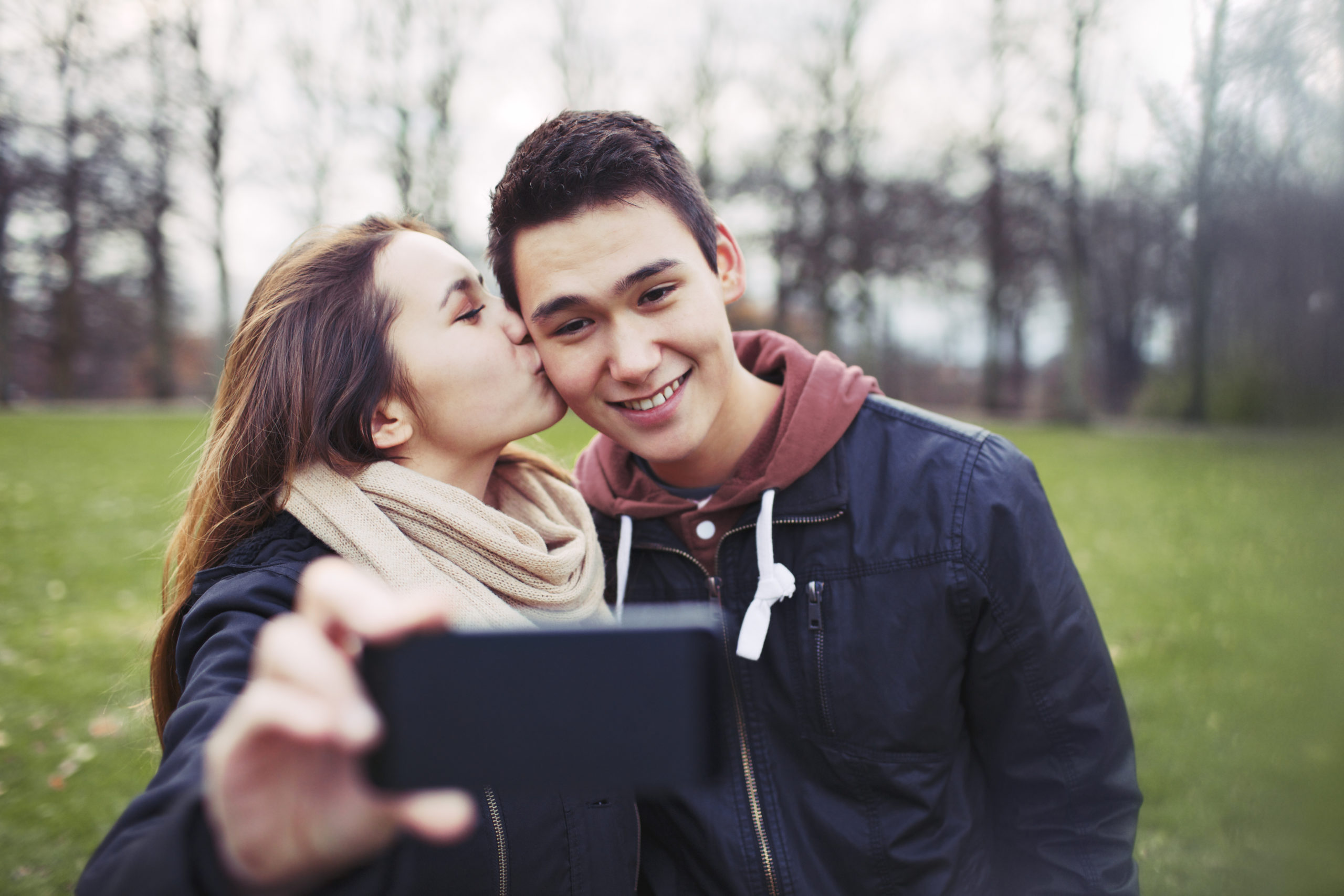 Young teenage couple take photo in park